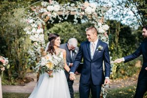 bride-and-groom-under-flower-arch-with-eucalyptus-dahlias