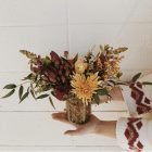 fall floral arrangement being held by two hands